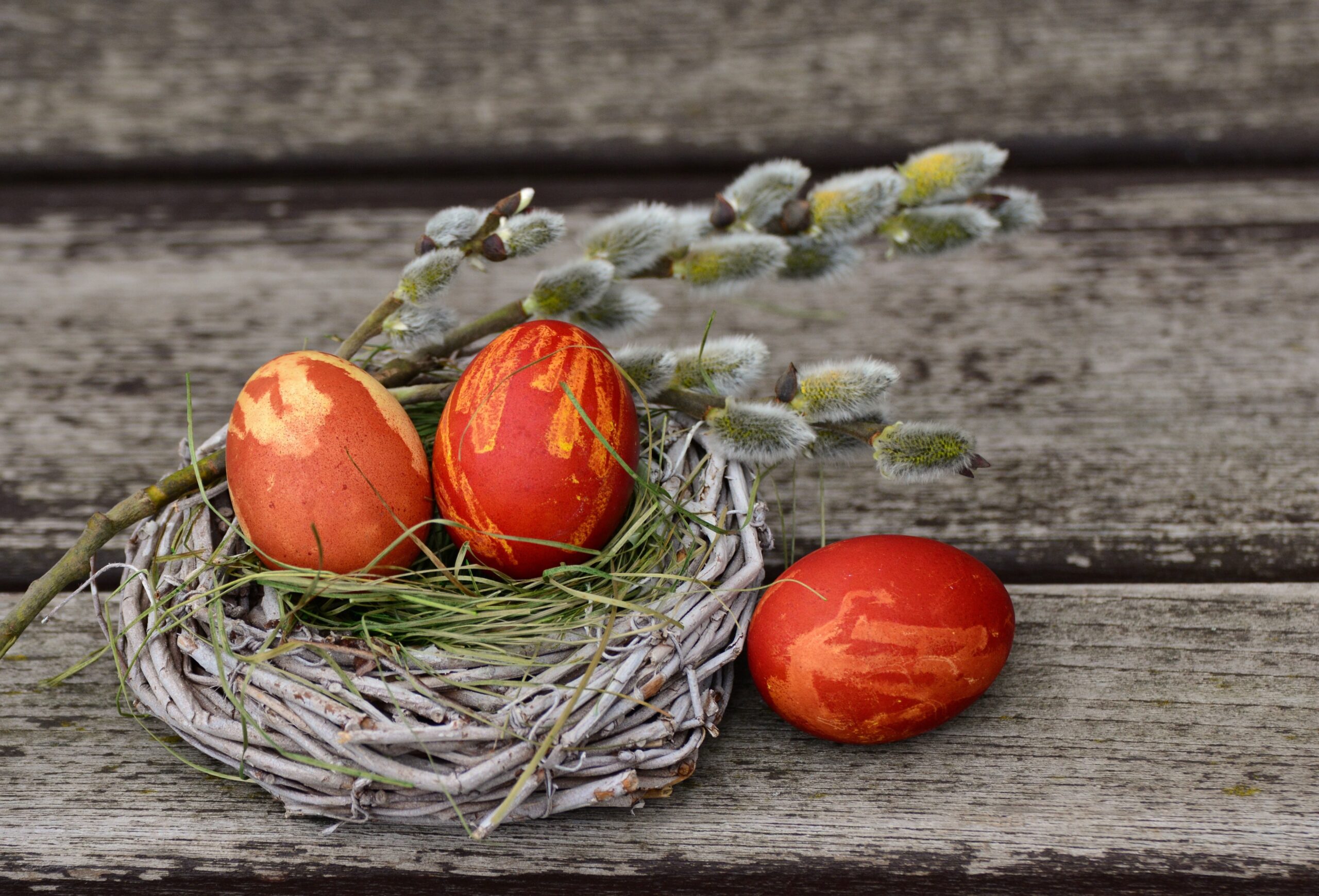 Jajka pisanki w koszyku obok bazie.